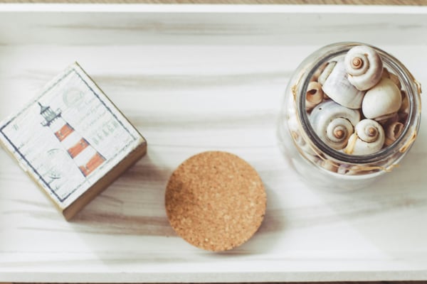 Coastal welcome tray with a lighthouse card, seashells, and a cork coaster